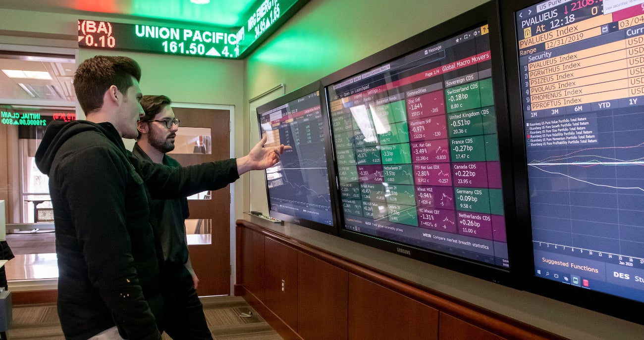 Students examining financial trends on screens in the Dykman Trading Room.